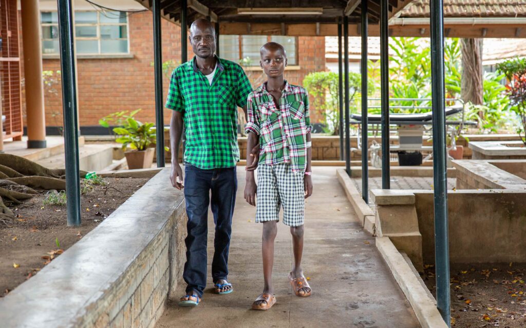 Sipiriano, Isaac’s father (left), supports Isaac outside the hospital.