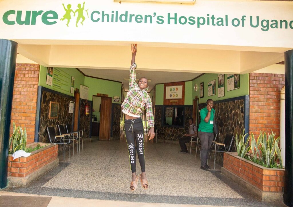 Isaac jumps to touch an overhead beam, something he could not do when he first arrived at CURE Uganda.